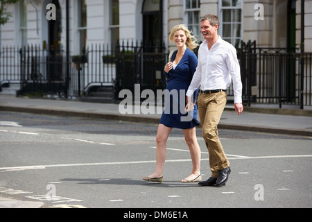 Paar mit schwangere Frau Crossing City Road Stockfoto