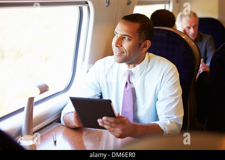 Geschäftsmann pendeln auf Zug mit Digital-Tablette Stockfoto