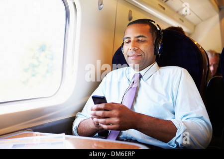 Geschäftsmann entspannend auf Zug anhören von Musik Stockfoto