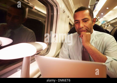 Geschäftsmann pendeln zur Arbeit auf dem Zug und mit Laptop in der Nacht Stockfoto