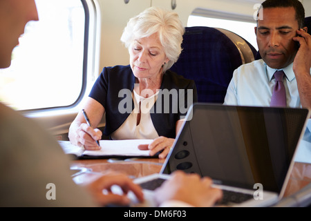 Geschäftsleute auf Zug mit digitalen Geräten Stockfoto
