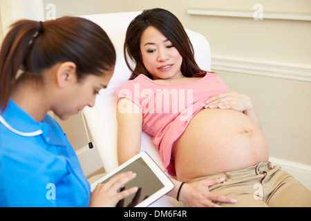 Krankenschwester mit Digital-Tablette In Treffen mit schwangere Frau Stockfoto