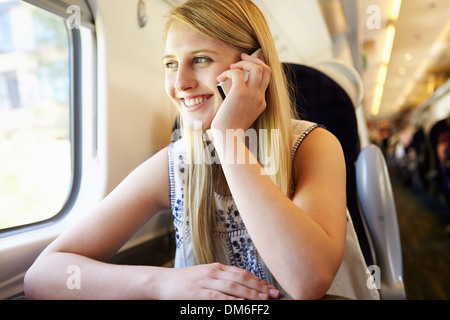 Teenager-Mädchen mit Handy auf Zugfahrt Stockfoto