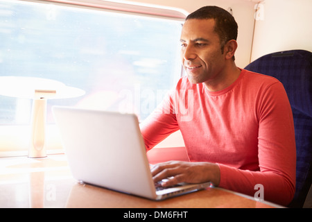 Mann mit Laptop im Zug Stockfoto