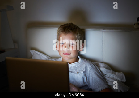 Boy mit Laptop im Bett in der Nacht Stockfoto