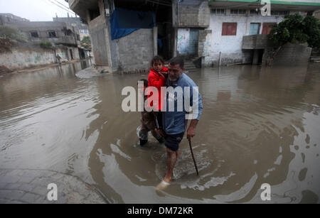 Gaza, Palästinensische Gebiete. 12. Dezember 2013. Ein palästinensischer Mann trägt seine Tochter entlang einer überfluteten Straße folgende Starkregen in Gaza-Stadt am 12. Dezember 2013 als eine Winter-Wetter-Front die Region getroffen. Im Gaza-Streifen, die in den Fängen einer Ölkrise wurde, die Krankenhäuser, Abwasserentsorgung und Kanalisation betroffen hat, sintflutartigen Regenfällen füllten die Straßen mit Hochwasser und überquellenden Abwasser und zwang die Schließung von Schulen und Banken. : Bildnachweis Majdi Fathi/NurPhoto: Majdi Fathi/NurPhoto/ZUMAPRESS.com/Alamy Live-Nachrichten Stockfoto