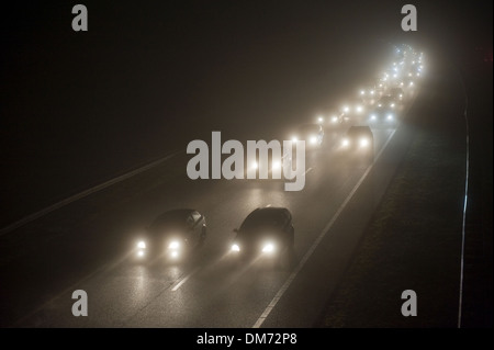 Ein Konvoi an einem nebligen Abend auf einer Autobahn im Dezember in den Niederlanden Stockfoto