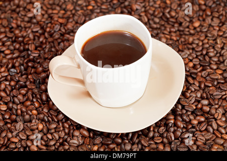 Tasse Kaffee auf Sauser und gerösteten Kaffeebohnen Stockfoto