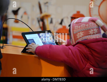 Berlin, Deutschland. 3. Dezember 2013. Ein Kind spielt mit einem ausgestellten Tablettcomputer in einem Einkaufszentrum in Berlin, Deutschland, 3. Dezember 2013. Foto: Jens Kalaene/Dpa/Alamy Live News Stockfoto