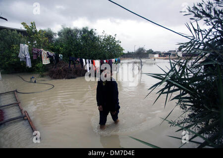 Rafah, Gaza-Streifen, Palästinensische Gebiete. 12. Dezember 2013. Ein palästinensischer Jugendlicher Spaziergänge in einer überfluteten Straße folgende Starkregen an einem stürmischen Tag in Rafah im südlichen Gazastreifen, 12. Dezember 2013. Straßen im Gaza-Streifen sind überflutet, nach nur drei Stunden von heavy Rain die schwere infrastrukturelle Schäden verursacht und überschwemmte mehrere Häuser Credit: Ashraf Amra/APA Images/ZUMAPRESS.com/Alamy Live News Stockfoto