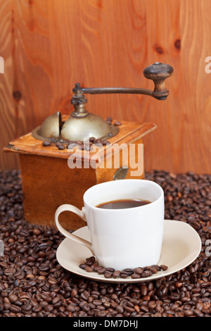 Tasse Kaffee und Kaffeebohnen mit Retro-manuelle Mühle in der Nähe von Holzwand Stockfoto