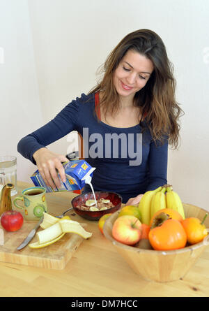 Berlin, Deutschland. 2. Dezember 2013. Eine junge Frau gießt Milch über Getreide in einer Schüssel in Berlin, Deutschland, 2. Dezember 2013. Foto: Jens Kalaene - MODEL RELEASED/Dpa/Alamy Live News Stockfoto