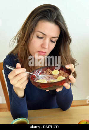 Berlin, Deutschland. 2. Dezember 2013. Eine junge Frau schaut moody eine Schüssel Müsli in ihren Händen in Berlin, Deutschland, 2. Dezember 2013. Foto: Jens Kalaene - MODEL RELEASED/Dpa/Alamy Live News Stockfoto