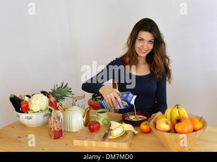 Berlin, Deutschland. 2. Dezember 2013. Eine junge Frau gießt Milch über Getreide in einer Schüssel in Berlin, Deutschland, 2. Dezember 2013. Foto: Jens Kalaene - MODEL RELEASED/Dpa/Alamy Live News Stockfoto