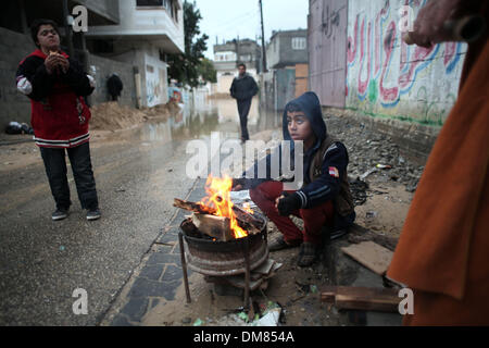 Gaza, Palästinensische Gebiete. 12. Dezember 2013. Ein palästinensischer Jugendlicher wärmt selbst um ein Feuer, wie im Hintergrund zu sehen, eine Straße überflutet nach starke Regenfällen an einem stürmischen Tag in Gaza-Streifen, 12. Dezember 2013 nördlichen. Straßen im Gaza-Streifen sind überflutet nach nur drei Stunden von heavy Rain die schwere infrastrukturelle Schäden verursacht und mehrere Häuser überflutet. : Bildnachweis Ahmed Deeb/NurPhoto: Ahmed Deeb/NurPhoto/ZUMAPRESS.com/Alamy Live-Nachrichten Stockfoto