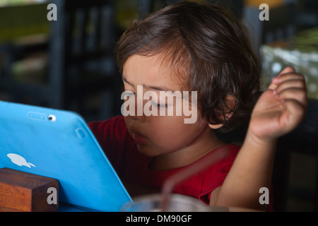 Ein kleines halbe Thai halbe amerikanische Kind spielt mit einem Computer - THAILAND Stockfoto