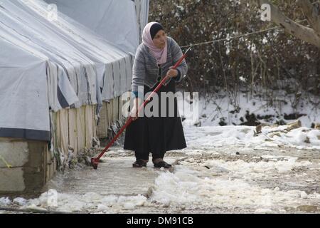 Rechtsanwaltskammer, Libanon. 12. Dezember 2013. Ein syrischer Flüchtling löscht Schnee in einem Flüchtlingslager im Bekaa-Tal im Osten Libanon nach einem Schneesturm am 12. Dezember 2103. Der Schneesturm "Alexa" schlug Libanon Dienstagabend bringt Schnee in höheren Lagen und sintflutartigen Regen anderswo, begleitet von starken Winden. Die Vereinten Nationen und seine Partnerorganisationen Hilfsmaßnahmen für die mehr als 800.000 syrische Flüchtlinge im Libanon Hochfahren sind, die durch Regen, Schneefall und eisige Temperaturen als einen harten Winter Schüttelfrost waren, den Sturm bewegt sich in der gesamten Region, sagte UN-Beamten hier am Freitag. Stockfoto