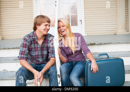 Junges Paar sitzt auf Schritte mit Koffern. Stockfoto