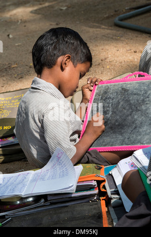 Indische Bauerndorf Schuljunge auf einem Kreide-Tablet in einer externen Klasse schreiben. Andhra Pradesh, Indien Stockfoto