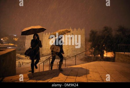 Jerusalem, Jerusalem, Palästina. 12. Dezember 2013. Die Menschen gehen vor Damaskus-Tor während eines Schneesturms in der Jerusalemer Altstadt am 12. Dezember 2013. Jerusalem ist bedeckt mit Schnee Donnerstag, der schwersten Schneesturm trifft der City seit 1953 als Meteorologen genannt Credit: Saeed Qaq/APA Images/ZUMAPRESS.com/Alamy Live News Stockfoto