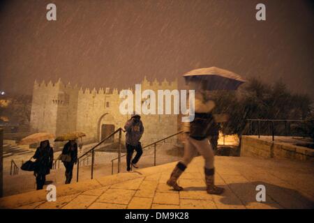 Jerusalem, Jerusalem, Palästina. 12. Dezember 2013. Die Menschen gehen vor Damaskus-Tor während eines Schneesturms in der Jerusalemer Altstadt am 12. Dezember 2013. Jerusalem ist bedeckt mit Schnee Donnerstag, der schwersten Schneesturm trifft der City seit 1953 als Meteorologen genannt Credit: Saeed Qaq/APA Images/ZUMAPRESS.com/Alamy Live News Stockfoto