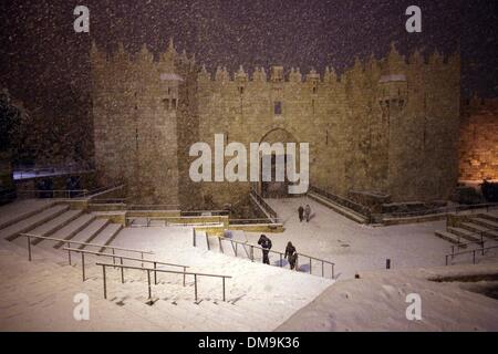 Jerusalem, Jerusalem, Palästina. 12. Dezember 2013. Die Menschen gehen vor Damaskus-Tor während eines Schneesturms in der Jerusalemer Altstadt am 12. Dezember 2013. Jerusalem ist bedeckt mit Schnee Donnerstag, der schwersten Schneesturm trifft der City seit 1953 als Meteorologen genannt Credit: Saeed Qaq/APA Images/ZUMAPRESS.com/Alamy Live News Stockfoto