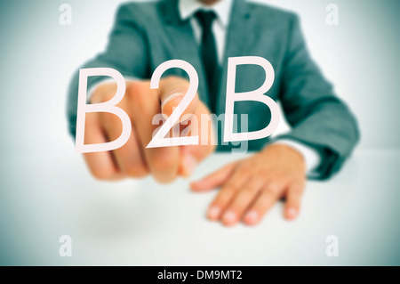 Mann in einem Anzug sitzt in einer Tabelle auf das Wort B2B, Business-to-Business, geschrieben im Vordergrund Stockfoto