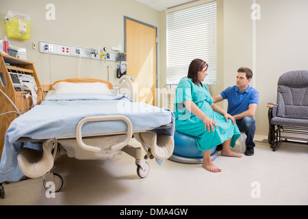 Gymnastikball im Krankenhaus bei schwangeren Frau auf Mann Stockfoto