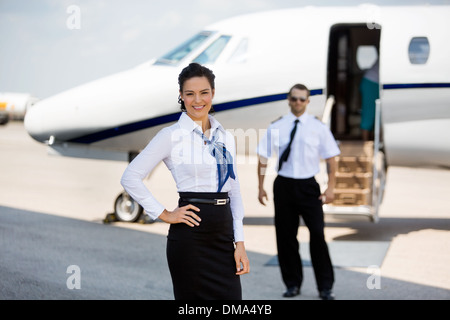 Zuversichtlich Stewardessen lächelnd mit Pilot und Privatjet In Bac Stockfoto