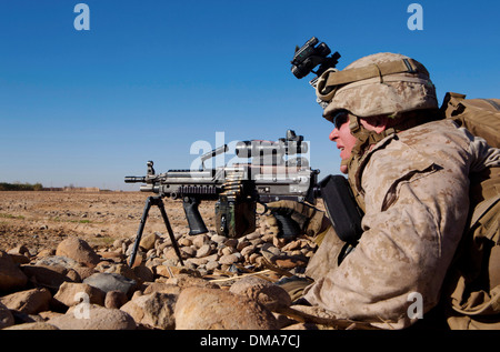 Ein US-Marine umfasst ein offenes Feld mit einem leichten Maschinengewehr M249 bei einem Feuergefecht mit Aufständischen 4. Dezember 2013 in der Nähe von Bari Gul Basar im Bezirk Nad Ali, Provinz Helmand, Afghanistan. Stockfoto