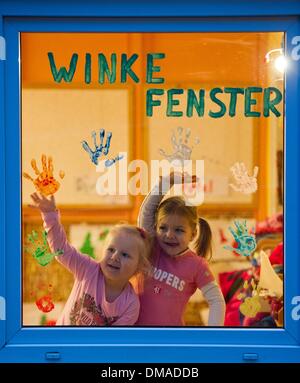 Frankfurt Oder, Deutschland. 6. Dezember 2013. Zwei Mädchen winken die Winke-Fenster (beleuchtet: winken-Fenster) des Kindergartens Glassteinen in Frankfurt Oder, Deutschland, 6. Dezember 2013. Kinder können ihren Eltern aus dem Fenster Welle, wenn sie die Kinder in der Tagesstätte verlassen. Foto: Patrick Pleul/ZB/Dpa/Alamy Live News Stockfoto