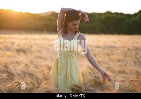 Junge Frau im Kleid stehen in einem Maisfeld bei Sonnenuntergang Stockfoto