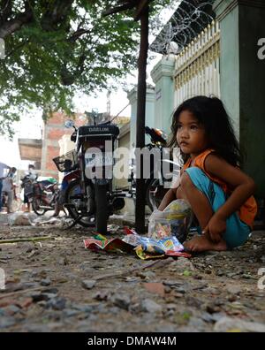 Phnom Penh, Kambodscha. 10. Dezember 2013. Eine Mädchen spielt im Chhba Anmpov Slum auf dem Gelände einen Friedhof in Phnom Penh, Kambodscha, 10. Dezember 2013. Kambodscha ist eines der 20 Länder mit den höchsten Raten von Unterernährung bei Kindern. Rund 670.000 Waisenkinder leben in Kambodscha. Jedes 22. Kind stirbt im ersten Jahr des Lebens. Mehr als ein Drittel der Bevölkerung lebt von weniger als einem Dollar pro Tag. Foto: Jens Kalaene/Dpa/Alamy Live News Stockfoto