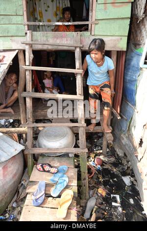 Phnom Penh, Kambodscha. 10. Dezember 2013. Ein Mädchen kommt aus einer Hütte in den Slum "Andong Bei Village" in Phnom Penh, Kambodscha, 10. Dezember 2013. Kambodscha ist eines der 20 Länder mit den höchsten Raten von Unterernährung bei Kindern. Rund 670.000 Waisenkinder leben in Kambodscha. Jedes 22. Kind stirbt im ersten Jahr des Lebens. Mehr als ein Drittel der Bevölkerung lebt von weniger als einem Dollar pro Tag. Foto: Jens Kalaene/Dpa/Alamy Live News Stockfoto