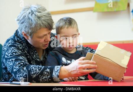 Dresden, Deutschland. 5. Dezember 2013. Fünf-jährige Valentino mit Down Syndrom sitzt mit Ergotherapeut Ines Maennig während der Ergotherapie in einem Therapieraum im Sociopediatric-Zentrum (SPZ) am Klinikum Dresden-Neustadt in Dresden, Deutschland, 5. Dezember 2013. (Model-Release verfügbar) Foto: Sebastian Kahnert/Dpa/Alamy Live News Stockfoto