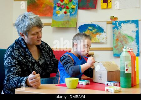 Dresden, Deutschland. 5. Dezember 2013. Fünf-jährige Valentino mit Down Syndrom sitzt mit Ergotherapeut Ines Maennig während der Ergotherapie in einem Therapieraum im Sociopediatric-Zentrum (SPZ) am Klinikum Dresden-Neustadt in Dresden, Deutschland, 5. Dezember 2013. (Model-Release verfügbar) Foto: Sebastian Kahnert/Dpa/Alamy Live News Stockfoto