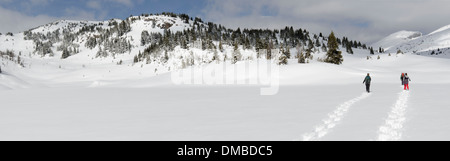 3 Personen schneit auf einem zugefrorenen See. In der Ferne, auf der rechten Seite sind einige von den Skipisten und Liftanlagen von Sunshine Village sichtbar Stockfoto