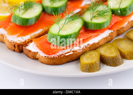 Lachs Sandwiches mit frische und eingelegte Gurke und Zitrone auf Platte Closeup Bild. Stockfoto