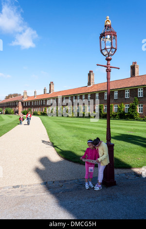 Zwei junge Mädchen schauen Sie sich eine Karte und touristische Führer am Eingang nach Hampton Court Palace, London, England, GB, UK. Stockfoto