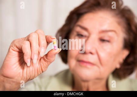 ältere Frau hält eine Pille Stockfoto