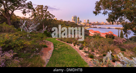 Ein Pfad schlängelt sich durch native Landschaftsgärten im Kings Park mit Perth City, den Swan River und Old Swan-Brauerei. Stockfoto