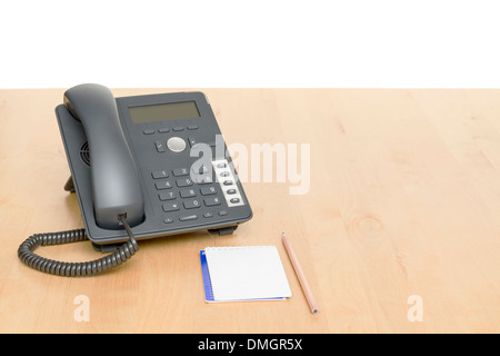 Telefon am Schreibtisch mit Notepad in weißem Hintergrund. Schreibtisch aus Holz. Stockfoto