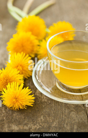 Kräutertee in Glasschale und Blumen auf Holztisch Stockfoto