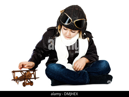 Fröhlicher niedlicher junge gekleidet wie ein zweiter Weltkrieg Pilot spielt mit hölzernen Flugzeug Spielzeug auf weißem Hintergrund. Vintage-look Stockfoto