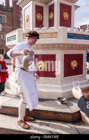 Schauspieler in historischen Kostümen dient Gläser Wein am Henry VIII Wein Brunnen Basis Gericht in Hampton Court Palace. Stockfoto