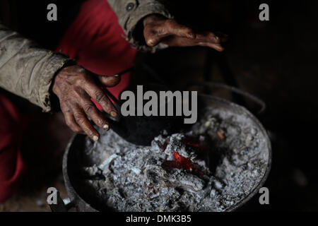 Gaza, Palästinensische Gebiete. 14. Dezember 2013. Ein palästinensischer Mann wärmt seine Hände über einem Kohle-Feuer in seinem Haus teilweise durch Regenwasser bei starkem Regen an einem stürmischen Tag in Gaza-Stadt am 14. Dezember, zerstörte 2013.Photo: Ahmed Deeb/NurPhoto Credit: Ahmed Deeb/NurPhoto/ZUMAPRESS.com/Alamy Live News Stockfoto