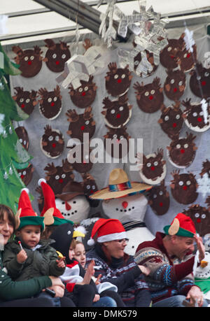 Wimborne, Dorset, Großbritannien. Dezember 2013. Die Zuschauer schauen sich die 25. Wimborne Save the Children Christmas Parade an. Kinder im Schwimmer tragen Weihnachtselfhüte mit Schneemännern und Rentiergesichtern. Quelle: Carolyn Jenkins/Alamy Live News Stockfoto