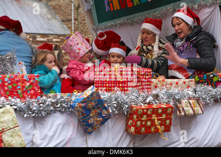 Wimborne, Dorset, Großbritannien. Dezember 2013. Die Zuschauer schauen sich die 25. Wimborne Save the Children Christmas Parade an. Frau und Kinder auf dem Wagen mit Weihnachtsgeschenken. Quelle: Carolyn Jenkins/Alamy Live News Stockfoto