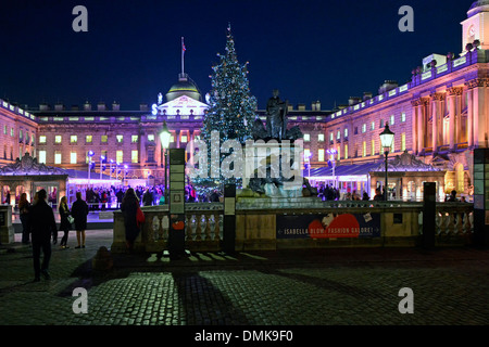 Leute beobachten Eisläufer Somerset House Weihnachtsbaum & Flutlicht Historische Fassade in der Nacht in temporären Winterhof Eislaufen Eisbahn London Großbritannien Stockfoto