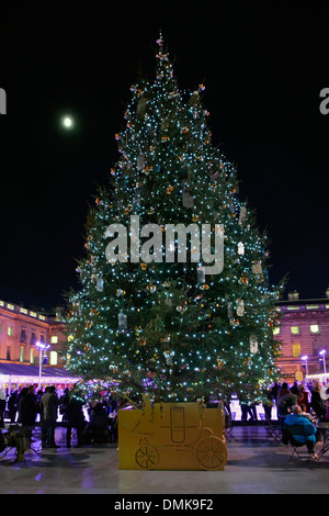 Nacht & Mond im Somerset House Innenhof mit Weihnachtsbaumschmuck & Menschen rund um die Eislaufbahn Eisbahn im Freien Eisbahn der Strand London England GB Stockfoto